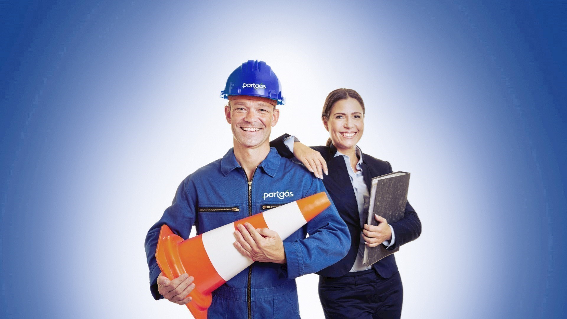 Homem com farda Portgás, junto a colega, segura um cone de sinalização